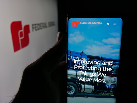 Stuttgart, Germany - 12-18-2025: Person holding smartphone with web page of US company Federal Signal Corporation on screen in front of logo. Focus on center of phone display.