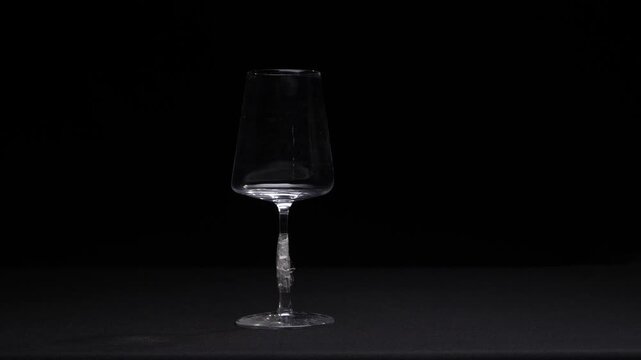 Hands carefully applying clear adhesive tape to the broken stem of a delicate wine glass, attempting to repair the damage against a dark background, symbolizing fragility and mending