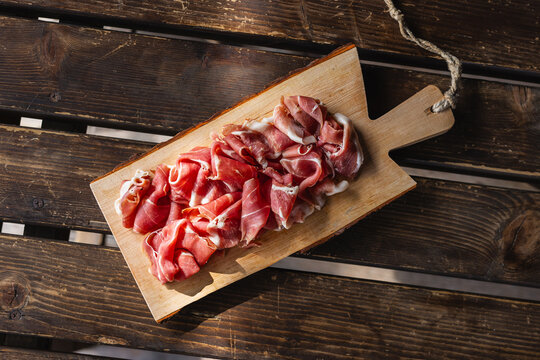 Platter of high quality raw ham (e.g. San Daniele or Sauris) served in an alpine setting.