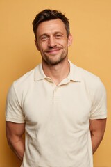 Obraz premium Confident Man Smiling in Light Polo Shirt Against Cream Background