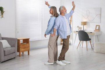 Happy senior couple dancing together at home. Space for text