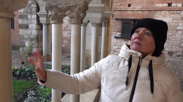 Woman touches stone column while exploring a historic location