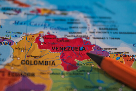 Una toma de primer plano que muestra el mapa de Venezuela resaltado en rojo, con un bol&iacute;grafo naranja apuntando al pa&iacute;s sobre un mapa pol&iacute;tico de Am&eacute;rica del Sur y el Caribe.