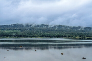 Lapland lake reflecting forest and foggy mountains