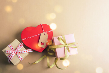 Valentines gift boxes with heart shaped present on warm background with soft festive lights. Top view, copy space