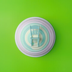 Colorful layers of dessert with a small chair on top against a bright green background