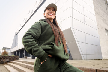Young woman in khaki sports suit with cap on street