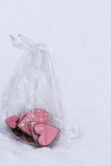 Pink iced heart gingerbread cookies packaged in plastic bag on snowy background