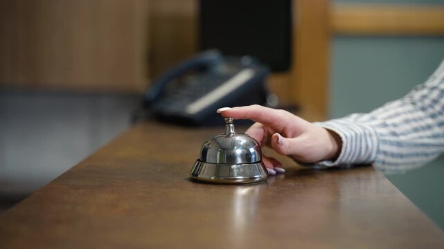 Woman's hand ringing hotel reception service bell