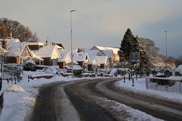 Snow covered main road with in a snowy neighbourhood background.Snow covered main road with in a snowy neighbourhood background. Empty road.Bus stop in distance