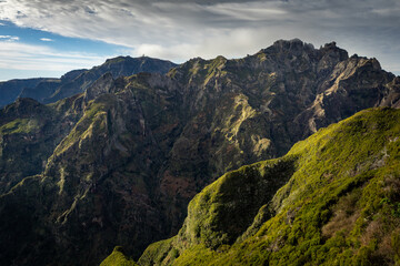 Panoramic view of rugged mountain ridges with the distant summit of Pico do Arieiro seen from the hiking trail leading to Pico Ruivo on Madeira Island, Portugal