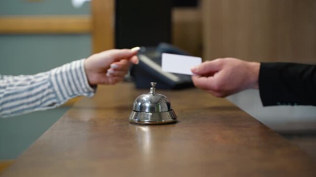 Woman giving key card to receptionist at hotel desk