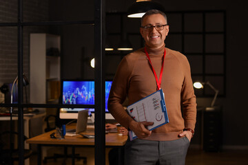 Male business analyst with diagrams in office at night. Data science concept