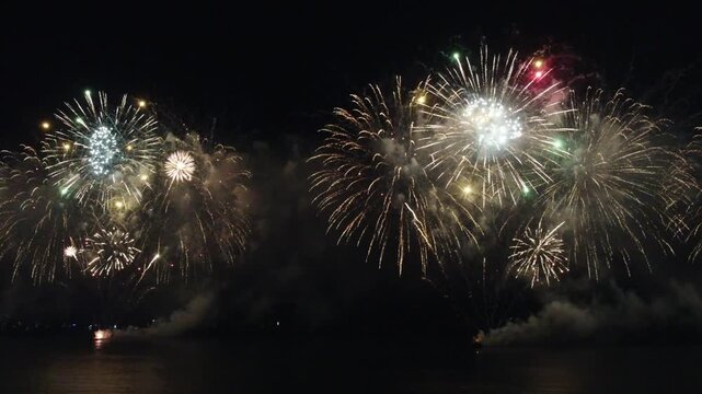 Fireworks display over the water at night.