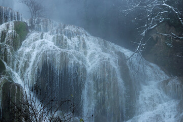 Krushuna Waterfalls in winter, Bulgaria. Beautiful waterfall with rapids and a strong flow of water. Waterfall in winter, steam rises from the water into the air. Natural background. Water. Close-up