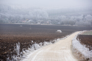 The road is covered in ice, the trees are covered in frost and the plowed field