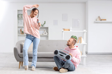 Young couple with microphone and boombox singing at home