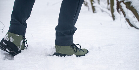 Hiking boots walking through fresh snow in winter landscape