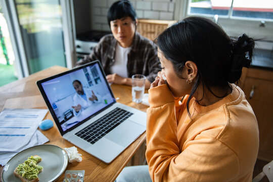 Young adult women in worried telehealth call at home