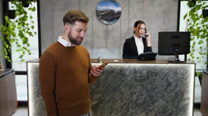 Man using smartphone waiting at hotel reception desk