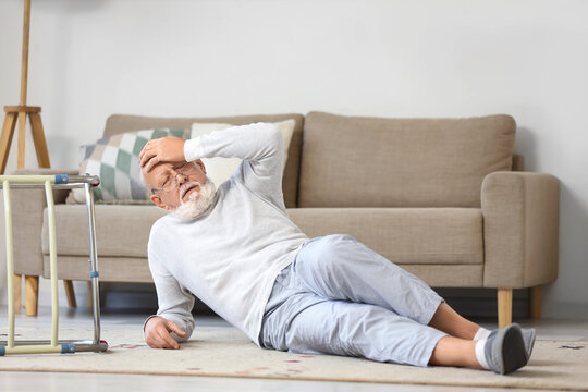 Senior man with walker lying on floor after fall at home