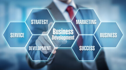 A business executive in a formal suit and tie interacts with an illuminated futuristic blue hexagonal digital interface showcasing key business concep