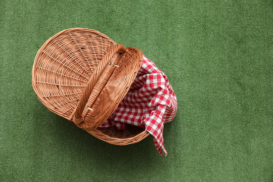 Rattan picnic basket with napkin on green background
