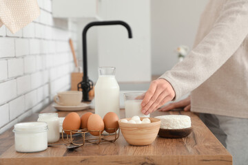 Young pregnant woman with different dairy products on counter in kitchen, closeup