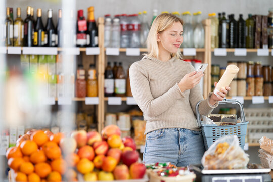 Female buyer checks suitability - scans QR code on jar of mayonnaise label in a grocery store