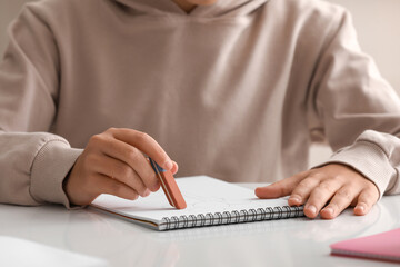 Fototapeta premium Child erasing something in notebook at table, closeup