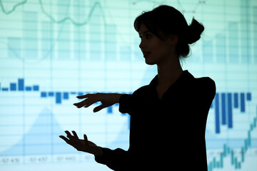 Silhouette of young businesswoman explaining something on charts background. Data science concept