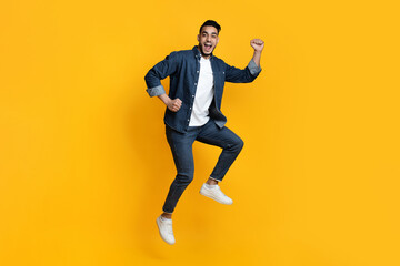 Excited handsome bearded arab guy jumping up in the air, raising fists up, copy space, catching...