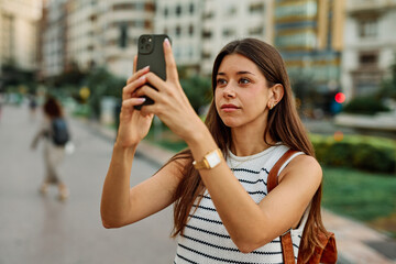 Young woman enjoys sunny day while using smartphone in urban setting, highlighting her joy and...