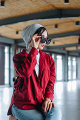Fototapeta premium Stylish veiled traveler pauses at modern terminal, adjusts sungl