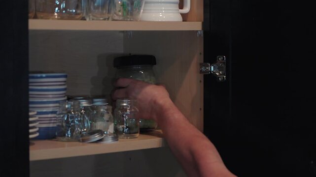 hand placing glass jar of homemade sauerkraut on pantry shelf