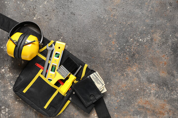 Wallet with money and builder's tool bag on grunge background