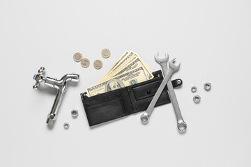 Wallet with money and plumber's tools on white background