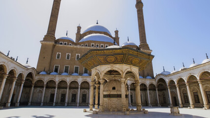 Beautiful view of an Egyptian mosque with tall minarets and domes under the bright sun, showcasing stunning Islamic architecture during a vacation.