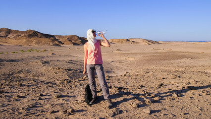 A woman enjoying a vacation in Egypt, drinking water while exploring the vast desert landscape during her travels.