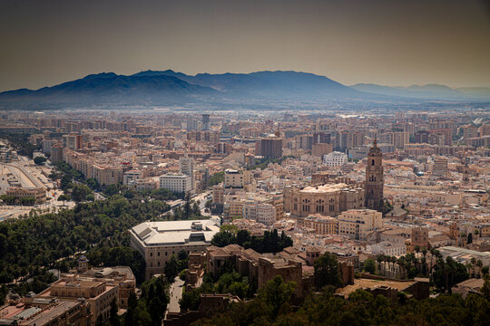 Vista panor&aacute;mica desde un mirador elevado que muestra la ciudad de M&aacute;laga, Espa&ntilde;a, integrando monumentos hist&oacute;ricos como la Catedral y la Alcazaba con el urbanismo moderno y las monta&ntilde;as de fondo bajo