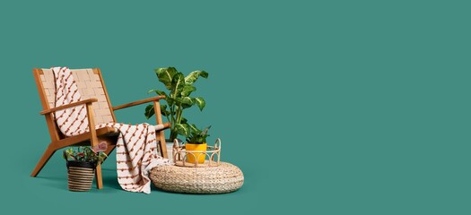 Armchair, rattan pouf and plants on green background with space for text