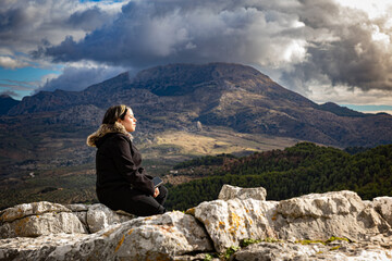 Retrato de una mujer joven sentada en paz sobre rocas, con los ojos cerrados en actitud de...