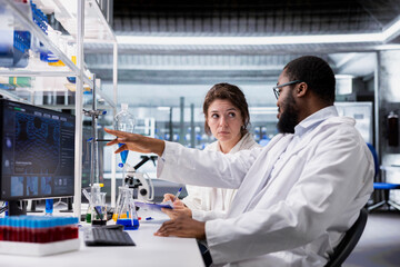 Diagnostic laboratory manager and trainee working together to process DNA patient data for clinical research. Lab team leader and intern use PC program to do genetic analysis diagnostics