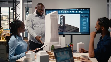 Urban development diverse team discussing property investment new strategy for project approval in a bright office setting, analyzing blueprints and 3D models on architectural software.