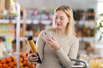Checking expiration date of spaghetti - female shopper scans QR code on label of spaghetti using...