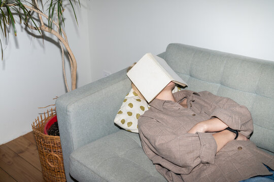 Person Sleeping on Couch with Book Covering Face