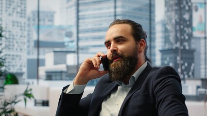 CEO multitasking and managing an important phone call with investors while he reviews financial reports on his laptop. Strategic decision making in corporate life at the workplace. Camera B.