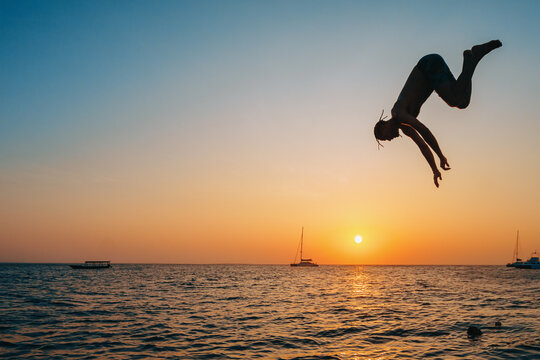 Silhouetted Man Diving into the Ocean at Sunset