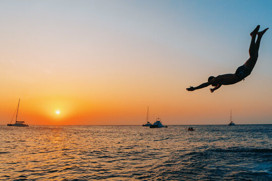 Silhouetted Man Diving into the Ocean at Sunset