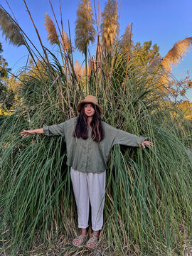 Woman Standing in Tall Grass Under Golden Sunset Light